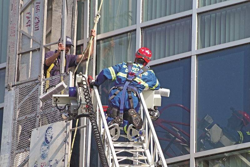 L’un des deux employés prisonniers de la nacelle attend d’être secouru par les pompiers. Photo Dominique St-Pierre